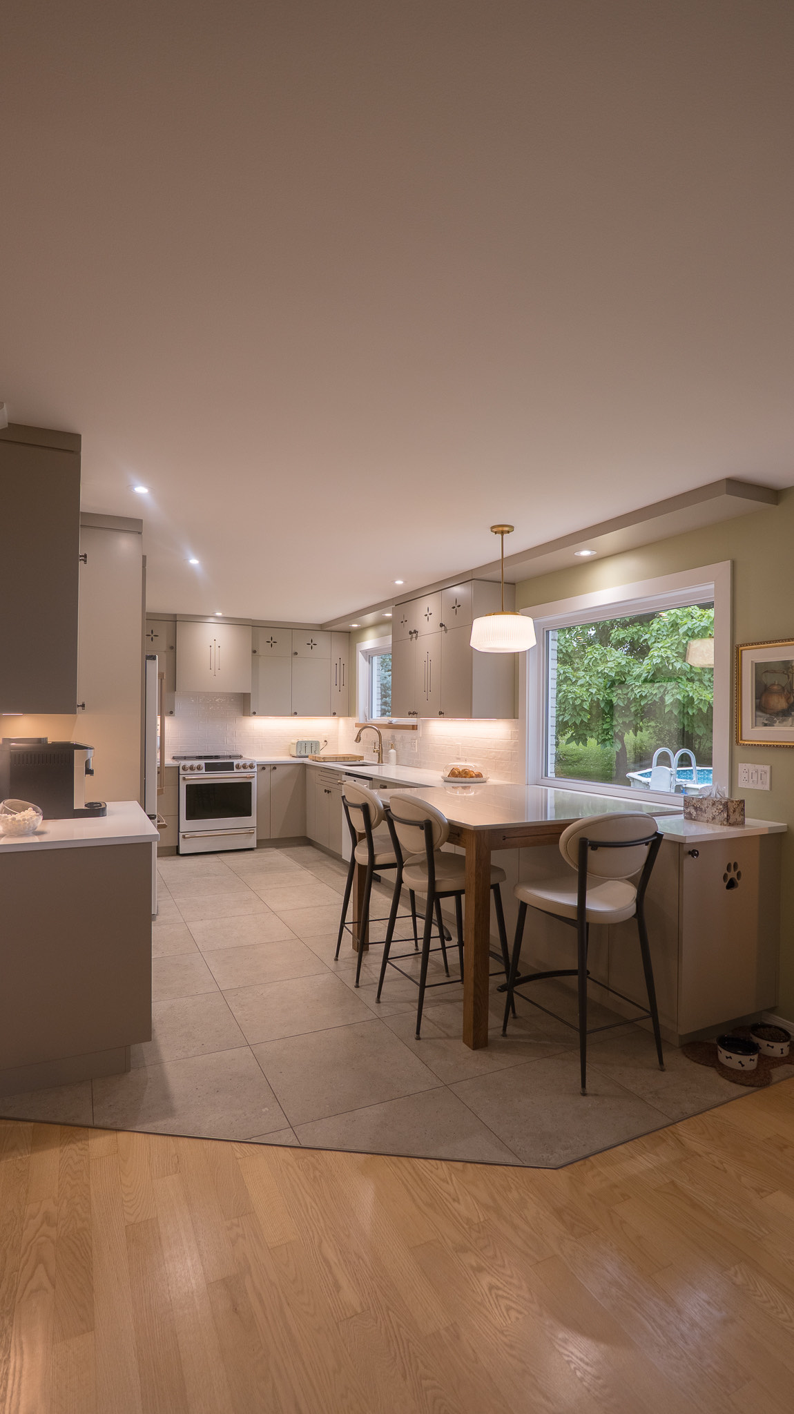 Cuisine sur mesure réalisée par Mobela : armoires taupe, comptoir de quartz et éclairage intégré, photographiée en soirée