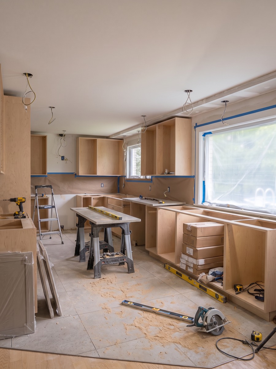 Chantier en cours : caissons d'armoires installés, ruban de protection et outils de l'atelier